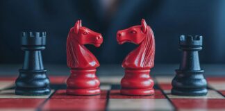 Investor placing chess pieces on a board shaped like a stock graph with bull and bear pieces, stocks, strategic market positioning. Copyright: KENZOGROW - stock.adobe.com